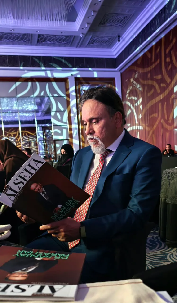 Dr. Sanjay Parashar, consultant plastic surgeon in Dubai, reading Insider Alseha magazine with his cover story